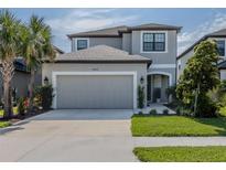 Two-story home featuring a well manicured lawn, a two-car garage, and a gray color scheme at 15364 Isla Palma Ln, Nokomis, FL 34275