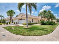 Charming single-story home featuring a two-car garage, lush lawn, and mature palm trees at 1799 Fountain View Cir, Venice, FL 34292