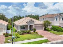 Charming single-story home featuring a clay tile roof, brick paver driveway, and well-manicured landscaping at 2034 Mesic Hammock Way, Venice, FL 34292