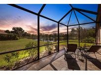 Screened patio featuring brick flooring with outdoor furniture and peaceful lake views at sunset at 2104 Batello Dr, Venice, FL 34292