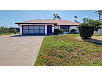 Charming single-story home with a two-car garage, a well-kept lawn, and attractive landscaping at 2194 Abalom St, Punta Gorda, FL 33980