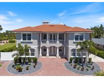 Stunning two-story home featuring a Spanish tile roof, balcony, and a brick paver driveway with circular garden beds at 2322 Bayshore Rd, Nokomis, FL 34275