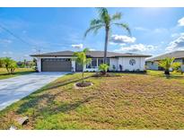 Charming single-story home featuring a well-maintained lawn, palm trees, and a two-car garage at 269 Mark Twain Ln, Rotonda West, FL 33947