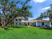 Charming two-story home with a sprawling lawn and mature trees offering curb appeal at 27215 Crosby Rd, Myakka City, FL 34251