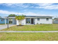 Charming single-story home featuring a well-manicured lawn and updated landscaping, complemented by a mature palm tree at 3616 Lalani Blvd, Sarasota, FL 34232