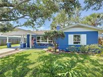 Charming blue home with a well-manicured lawn, carport, and colorful landscaping at 413 Valencia Rd, Venice, FL 34285