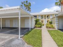 Inviting condo exterior with a carport, landscaped walkway, and second-story balconies in a bright, sunny setting at 418 Cerromar Ct # 158, Venice, FL 34293