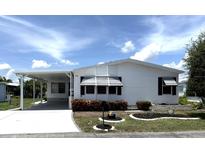 Charming single-story home with white siding, carport, well-manicured landscaping, and vibrant flowerbeds at 453 Sharks Pt, North Port, FL 34287