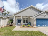 Charming home with a blue garage door, stone accents, and a welcoming porch at 460 Bard Rd, Venice, FL 34293