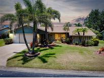 Charming home features a lush green lawn, mature palm trees, and a well-maintained two-car garage at 915 S Doral Ln, Venice, FL 34293