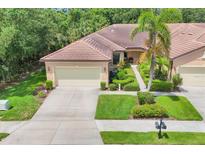 Beautiful aerial view of a home featuring lush landscaping, neutral colors, and a large driveway at 11103 Batello Dr, Venice, FL 34292