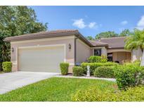 Charming single-story home with a tile roof, well-manicured lawn, and mature landscaping at 11103 Batello Dr, Venice, FL 34292