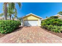 Detached one car garage with red and tan brick paver driveway and mature tropical landscaping at 11624 Garessio Ln, Sarasota, FL 34238