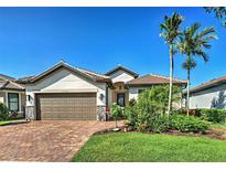 Charming single-story home boasts a brick driveway, two-car garage, and lush tropical landscaping at 13016 Rinella St, Venice, FL 34293