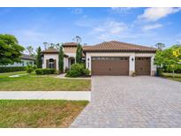 Charming home with a tile roof, three-car garage, paver driveway, and manicured lawn at 13280 Campanile Ct, Venice, FL 34293