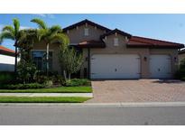 Charming home featuring a red tile roof, two-car garage, well-maintained landscaping and a brick driveway at 136 Positano Trl, Nokomis, FL 34275