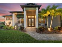 Charming home featuring a well-manicured lawn, inviting front entrance, and elegant double doors at 14398 Fort Worth Cir, Port Charlotte, FL 33981