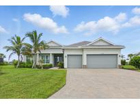 Charming single-story home with a three-car garage, beautiful landscaping, and a paver driveway at 15336 Spanish Point Dr, Port Charlotte, FL 33981