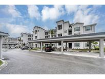 Condominium building with covered parking, showcasing a modern facade and well-maintained grounds at 17595 Opal Sand Dr # 205, Venice, FL 34293