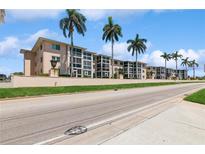 Inviting exterior view of multi-Gathering residence and palm trees with well-manicured lawn and street at 200 The Esplanade N # C19, Venice, FL 34285