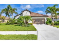 Beautiful single-story home featuring a tile roof, palm trees, and a well-maintained lawn at 213 Malina Ct, Nokomis, FL 34275