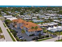 An aerial view of a beautiful condo complex with a terracotta roof, surrounded by lush greenery and palm trees at 235 Base E Ave # 207, Venice, FL 34285