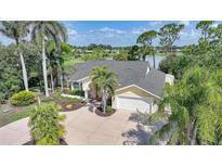 Charming yellow house featuring a well-manicured lawn, palm trees, and a circular driveway at 249 Hallcrest Ter, Port Charlotte, FL 33954