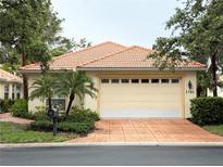 Charming single-story home featuring a tile roof, lush landscaping, and a two-car garage with an attractive brick driveway at 3790 Cadbury Cir # 40, Venice, FL 34293