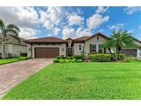 Charming home with a well-manicured lawn, lush landscaping, and a brown two-car garage at 4740 Royal Dornoch Cir, Bradenton, FL 34211