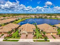 Stunning aerial view of the home with a spacious two-car garage, verdant landscaping and beautiful lake views at 21641 Winter Park Ct, Venice, FL 34293