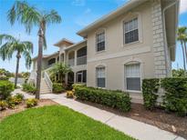 Beautiful condo building with tropical landscaping, sidewalks, and palm trees on a sunny day at 2204 L Pavia Blvd # 2204, Venice, FL 34292