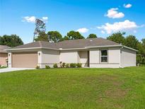 Charming single-story home with a well-manicured lawn and attached two-car garage on a sunny day at 2355 Allsup Ter, North Port, FL 34286