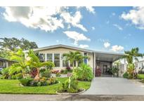 Charming home with well-manicured lawn, colorful tropical landscaping and a covered parking area and entry way at 239 Cutter Ct, North Port, FL 34287