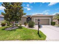Charming home featuring a well-manicured lawn, mature trees, and a two-car garage on a sunny day at 24536 Buckingham Way, Port Charlotte, FL 33980