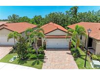 Charming villa featuring a tile roof, two-car garage, brick driveway and tropical landscaping at 257 Teramo Way, Nokomis, FL 34275