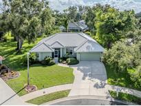 Beautiful single-story home boasts a well-manicured lawn, mature trees, and a spacious driveway at 337 Meadow Beauty Ct, Venice, FL 34293