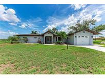 Charming single-story home with a well-manicured lawn, screened entryway and detached garage at 3376 Peace River Dr, Punta Gorda, FL 33983