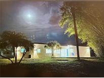 Night view of home with palm trees, green grass, and light reflecting off the exterior, creating a tranquil ambiance at 6821 Marius Rd, North Port, FL 34287