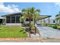 Charming single-story home with a well-manicured lawn, palm tree, carport, and screened-in porch at 738 Riverview Cir, North Port, FL 34287