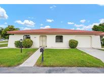 Charming single-story home featuring a red tile roof, well-maintained landscaping, and attached garage at 844 Senda Plata # 27, Venice, FL 34293