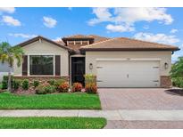 Beautiful single-story home with a tile roof, manicured lawn, and brick driveway at 11970 Lovegrass St, Venice, FL 34293