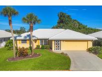 Charming single-story home with a well-maintained lawn, tropical palm trees, and a bright yellow exterior at 1614 Quail Lake Dr, Venice, FL 34293
