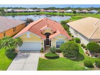 Beautiful home features a tile roof, well maintained landscaping, and a serene lake view at 1620 San Silvestro Dr, Venice, FL 34285