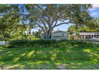 Charming home with a large tree providing shade, lush grass, and well-maintained landscaping at 2185 Park Rd, Venice, FL 34293