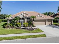 Inviting single-story home featuring a well-manicured lawn, mature landscaping, and a three-car garage at 2928 Seasons Blvd, Sarasota, FL 34240