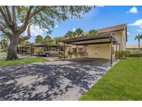 Condo exterior featuring covered parking, mature trees, and well-maintained landscaping on a sunny day at 330 Mission N Trl # B, Venice, FL 34285