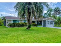 Charming single-story home featuring a lush green lawn and a mature palm tree in the front yard at 386 Nightingale Rd, Venice, FL 34293