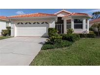 Charming single-story home featuring a red tile roof, well-manicured lawn, and an attached two-car garage at 4831 Summertree Rd, Venice, FL 34293