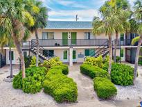 Two-story building with tropical landscaping, stairs, and walkway to the entrance at 614 Guild Dr # 10, Venice, FL 34285