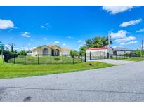 Charming yellow house with a gated entrance, lush lawn, and a clear blue sky at 102 Bayamo Dr, North Port, FL 34287